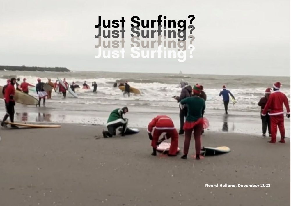 The photograph depicts people getting ready to surf at a beach. At the bottom of the landscape photograph is flat grey sand; in the middle are breaking waves and groups of people standing together on the sand and in shallow water. Some bend over or crouch beside surfboards lying on the ground. Several people wear red or green Santa suits, and one wears a tutu over a wetsuit. Above them is a grey, cloudy sky with the title 'Just Surfing?'.