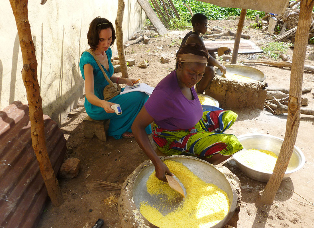 Lady roasting gari from yellow cassava in Tyo-Mu, Benue State, Nigeria and researcher Aurelie Bechoff recording temperature using infra-red thermometer.