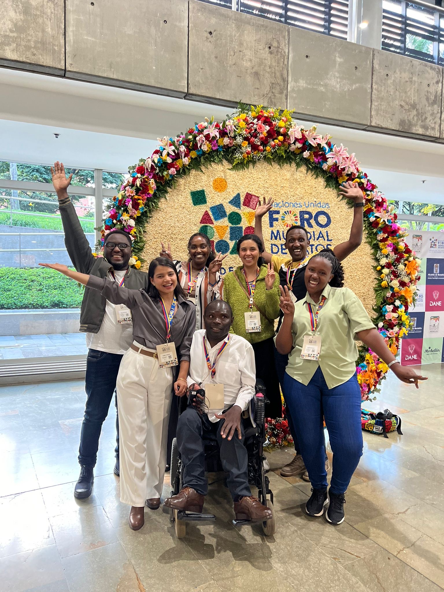 A group of seven young adults pose in front of the World Data Forum sign.
