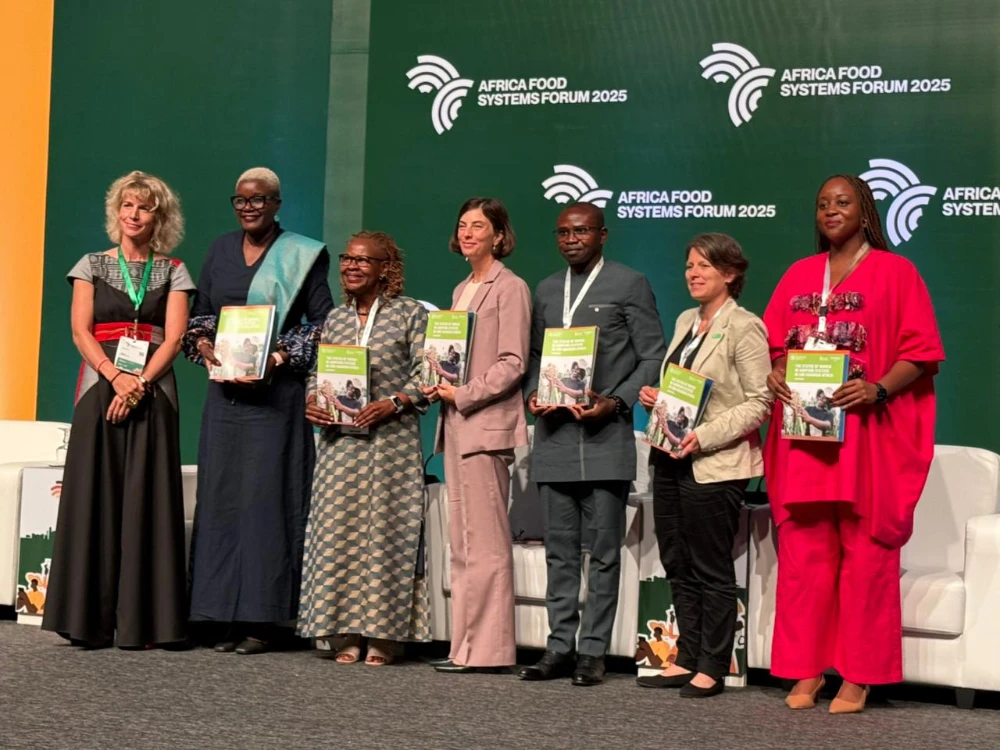 A group of women who co-authored the Women in Agrifood Systems in Sub-Saharan Africa overview report pose together at the AFS Forum, holding the printed report
