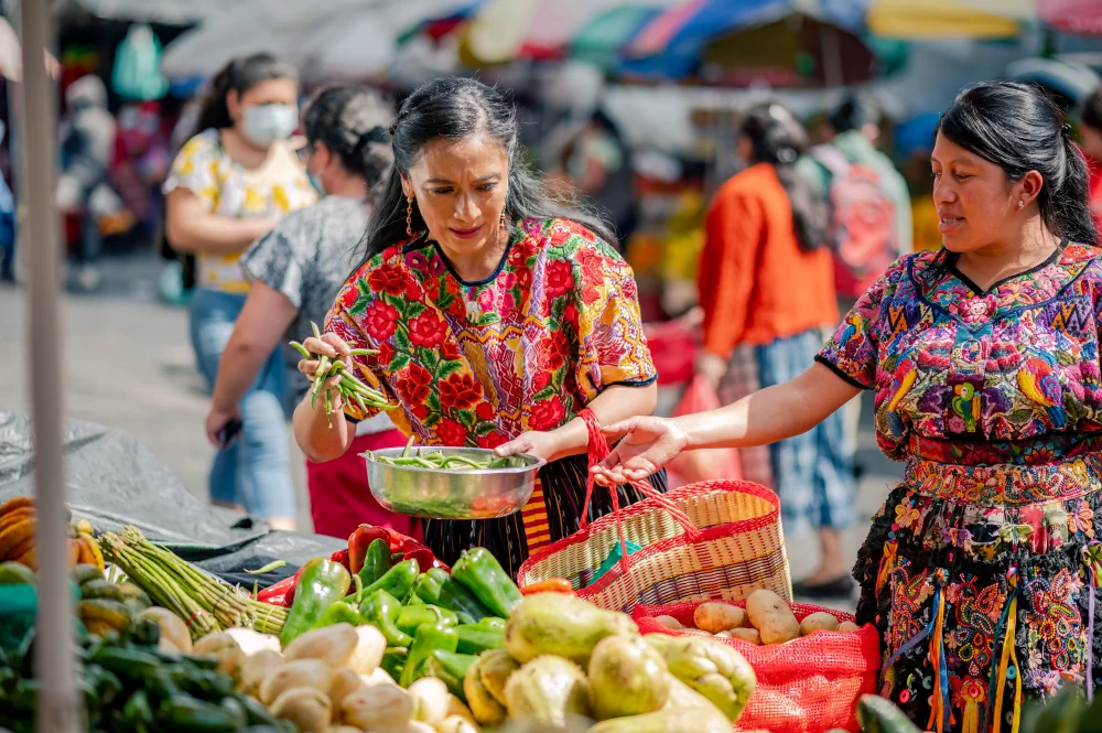 two woman looking at produce at a market